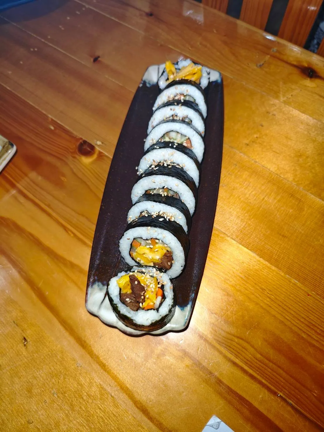 Halal kimbap rolls served on a slate platter at K-Uncle